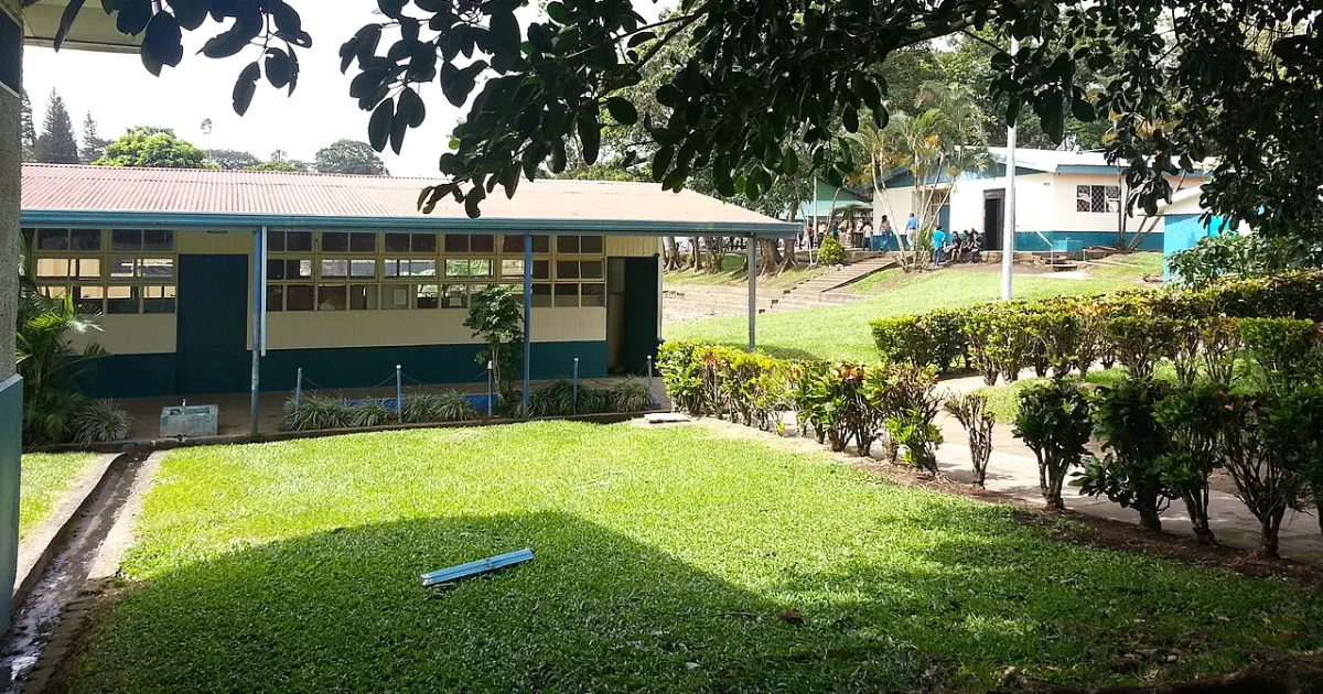Campus de un colegio en Tilarán, Costa Rica, con aulas de un piso, zonas verdes y estudiantes a lo lejos