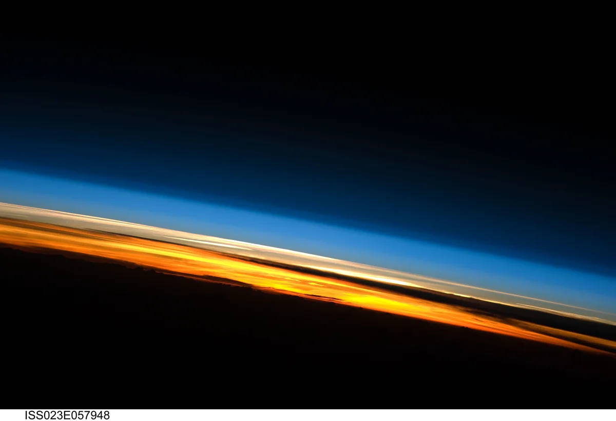 Vista de la atmósfera terrestre desde la Estación Espacial Internacional, con la curvatura del planeta al fondo. La franja anaranjada es la parte baja, donde está casi todo el aire; hacia arriba se aclara y se vuelve azul, y más arriba se oscurece hasta el negro del espacio. Imagen de la NASA, dominio público.