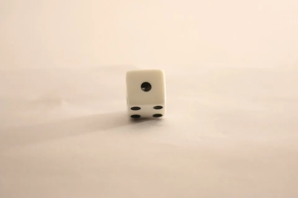 Dado común de seis caras. Las caras de uno y de cuatro puntos comparten una arista, así que no pueden quedar opuestas: en un dado corriente, cada par de caras opuestas suma siete, y el uno queda enfrente del seis. Imagen de Wikimedia Commons, Anton Ehrola, CC BY-SA 4.0.