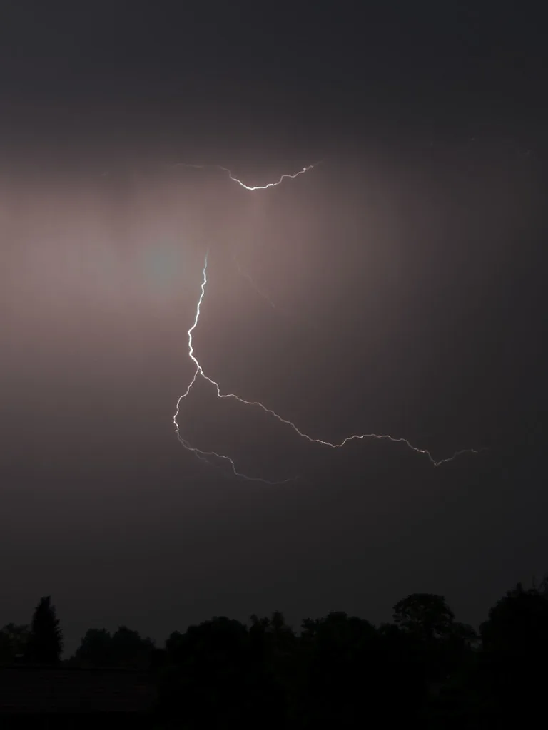 Un rayo cayendo durante una tormenta nocturna. Es electricidad estática en grande: las nubes acumulan carga, la diferencia con el suelo se vuelve enorme, y esa carga salta de golpe en una descarga que ilumina el cielo. Fotografía de Flickr, maartmeester, licencia BY-SA.
