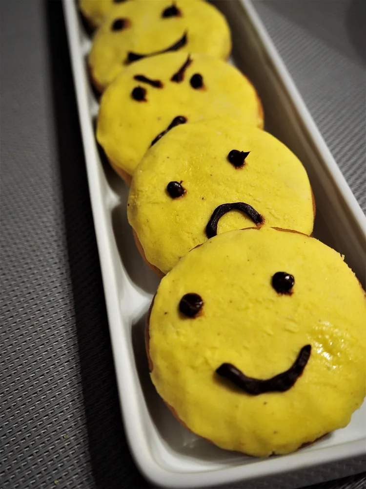 Galletas con caras: la de adelante sonríe (happy), la segunda tiene la boca hacia abajo (sad) y la tercera frunce las cejas (angry). La boca y las cejas te dicen la emoción. Foto: Eirini Pyrovolaki, Wikimedia Commons, CC BY-SA 4.0.