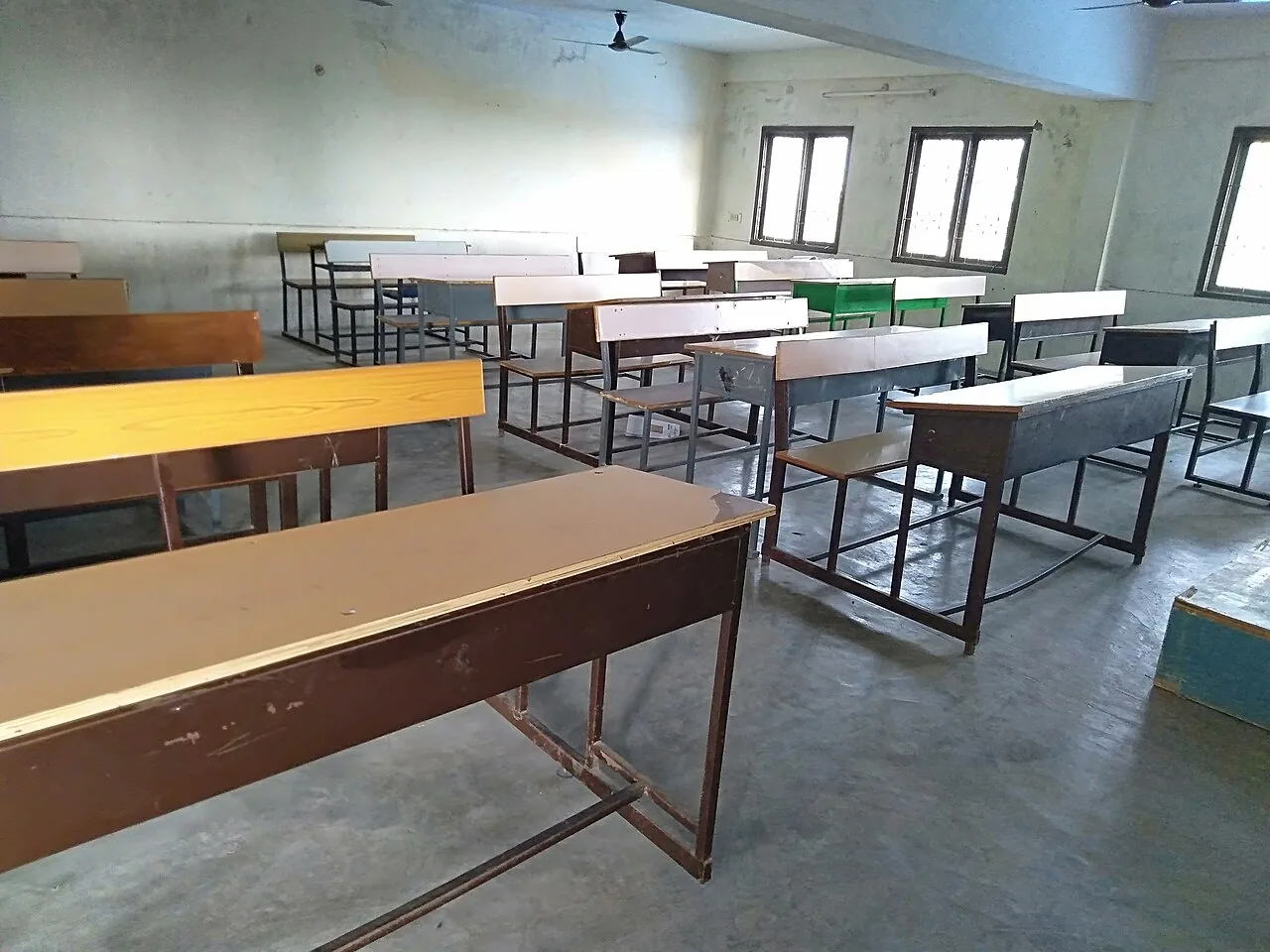 Pupitres de una escuela, vacíos antes de que empiece la clase. Con Sit down! los niños se sientan en ellos y con Stand up! se levantan. Foto: Saral Shots, Wikimedia Commons, CC0.