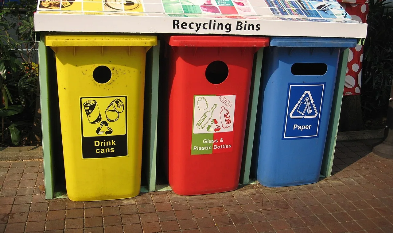 Basureros de reciclaje de colores: amarillo para latas, rojo para vidrio y plástico, azul para papel. Separar la basura así es recycle, reciclar. Foto: Terence Ong, Wikimedia Commons, CC BY 2.5 (recortada).