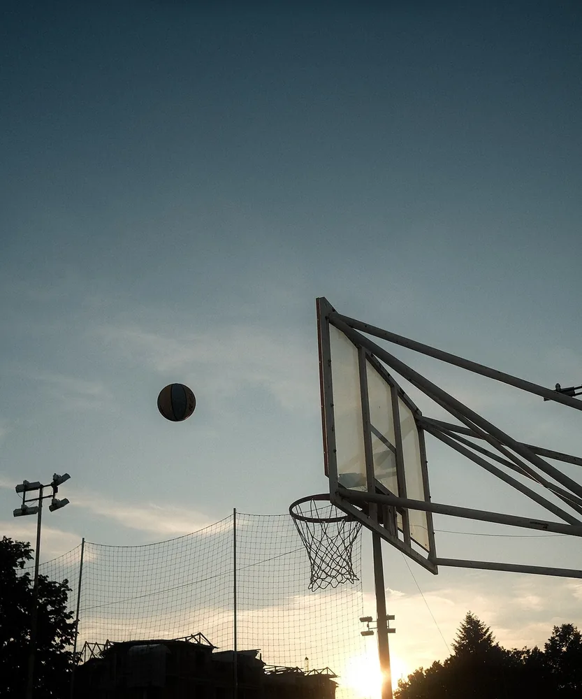 Una bola entrando al aro de baloncesto al atardecer. Do you want to play soccer or basketball? Foto: Shixart1985, Wikimedia Commons, CC BY 2.0 (recortada).