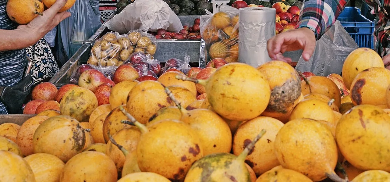 Granadillas, manzanas y bolsas de papas en un puesto de la feria del agricultor de Costa Rica. Las papas son potatoes. Foto: Bernal Saborio, Wikimedia Commons, CC BY-SA 2.0 (recortada).
