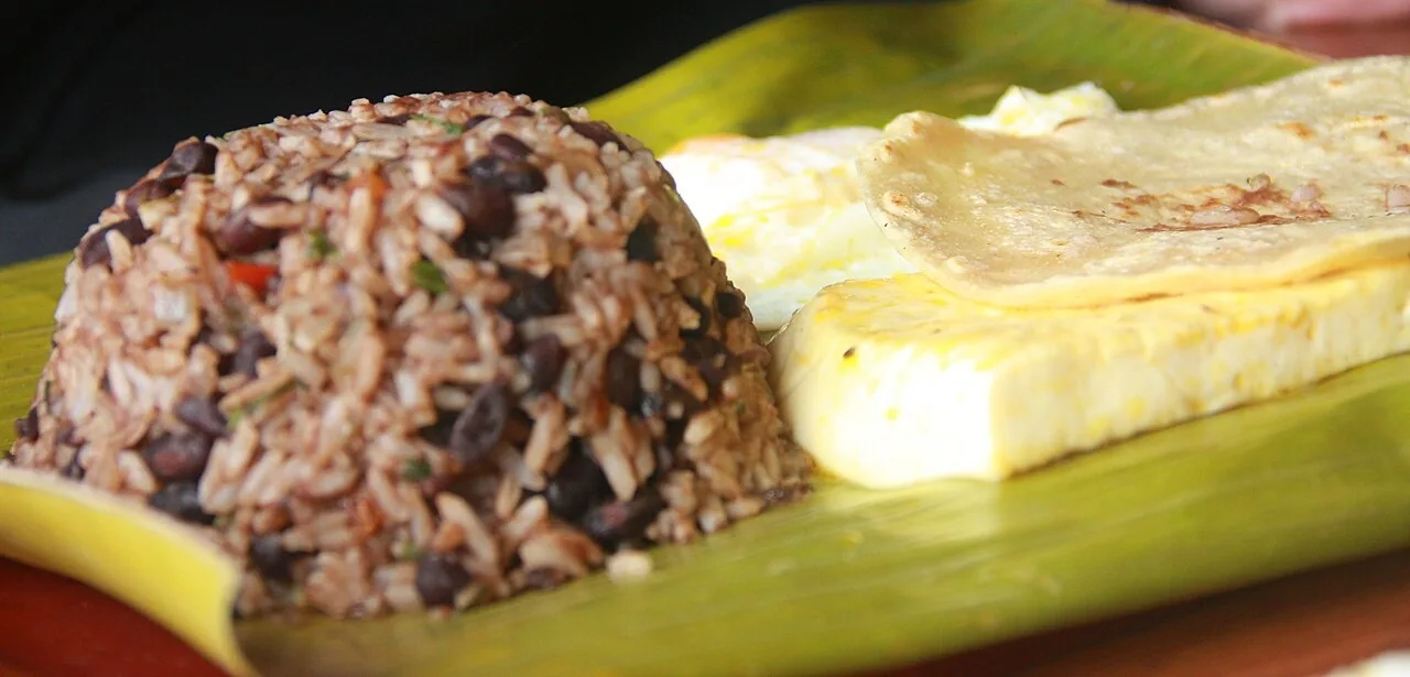 Gallo pinto con huevo, tortilla y queso sobre hoja de plátano. You should try gallo pinto! Foto: Legendre17, Wikimedia Commons, CC BY 3.0 (recortada).