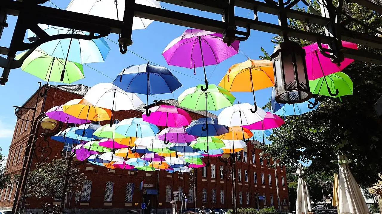 Sombrillas de colores colgadas sobre una calle. La sombrilla, umbrella, es lo que se lleva cuando está rainy. Foto: Szalax, Wikimedia Commons, CC0.