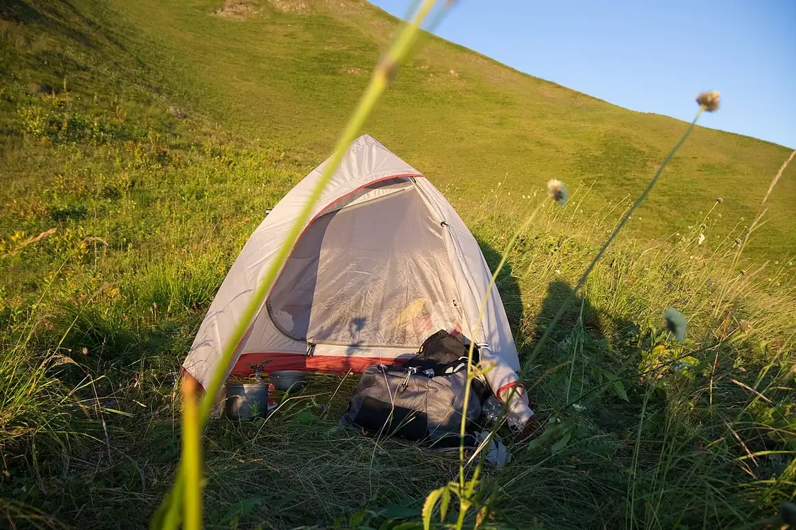 Una tienda de campaña en una ladera verde. I like camping, but I prefer staying at a hotel. Foto: Vyacheslav Argenberg, Wikimedia Commons, CC BY 4.0.