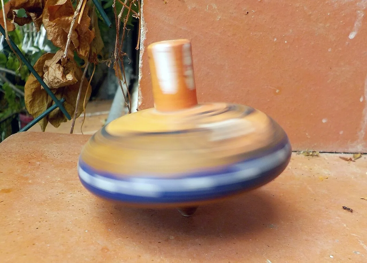 Un trompo de madera girando. How do you play with a spinning top? Foto: Albarubescens, Wikimedia Commons, CC BY-SA 4.0.