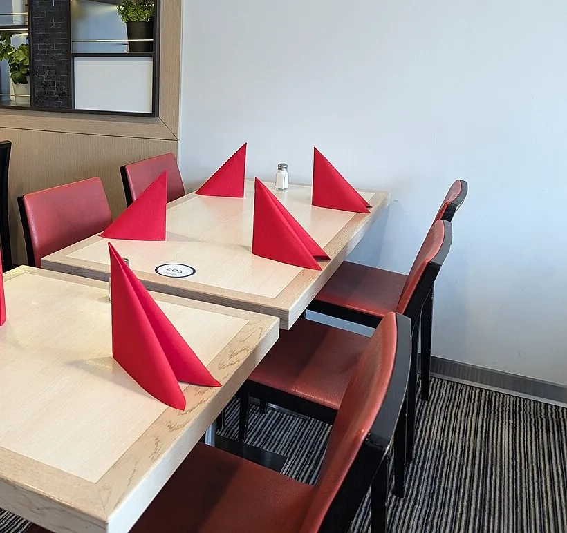 Mesas con servilletas rojas, listas para recibir a los invitados. Set the tables before the party. Foto: AleWi, Wikimedia Commons, CC BY-SA 4.0 (recortada).