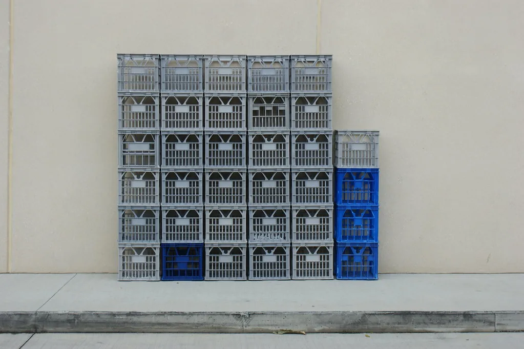 Cajones apilados contra una pared: el bloque grande tiene cinco columnas y seis cajones en cada una. Leído de un lado son 5 × 6 = 30, y leído del otro, 5 y 6 son divisores de 30: la misma relación mirada desde arriba o desde abajo. La pila corta de la derecha es lo que sobró y no alcanzó para armar otra columna. Imagen de flickr — elliott.bledsoe, licencia BY.