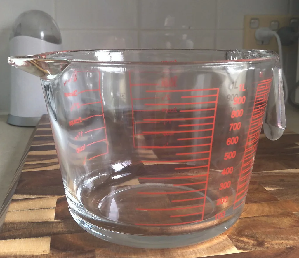 Una jarra de medir con dos escalas impresas en el mismo vidrio. La misma altura de agua se lee de dos maneras distintas y las dos dicen la misma cantidad, que es exactamente lo que pasa entre 1/2 y 2/4. Cambia con qué se mide, no cuánto hay. Imagen de flickr — David Jackmanson, licencia BY.