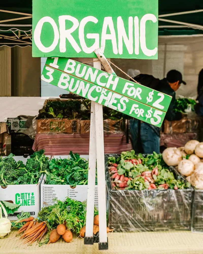 Un rótulo de precios en una feria: un manojo a un precio y tres manojos a otro. Comparar cuál conviene es exactamente comparar cantidades de dinero. Foto: Ella Olsson, Wikimedia Commons, CC BY 2.0.